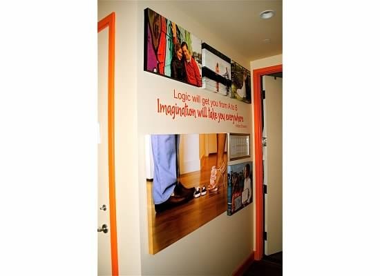 Hallway wall with family photo canvases, painted quote lettering, and orange door trim